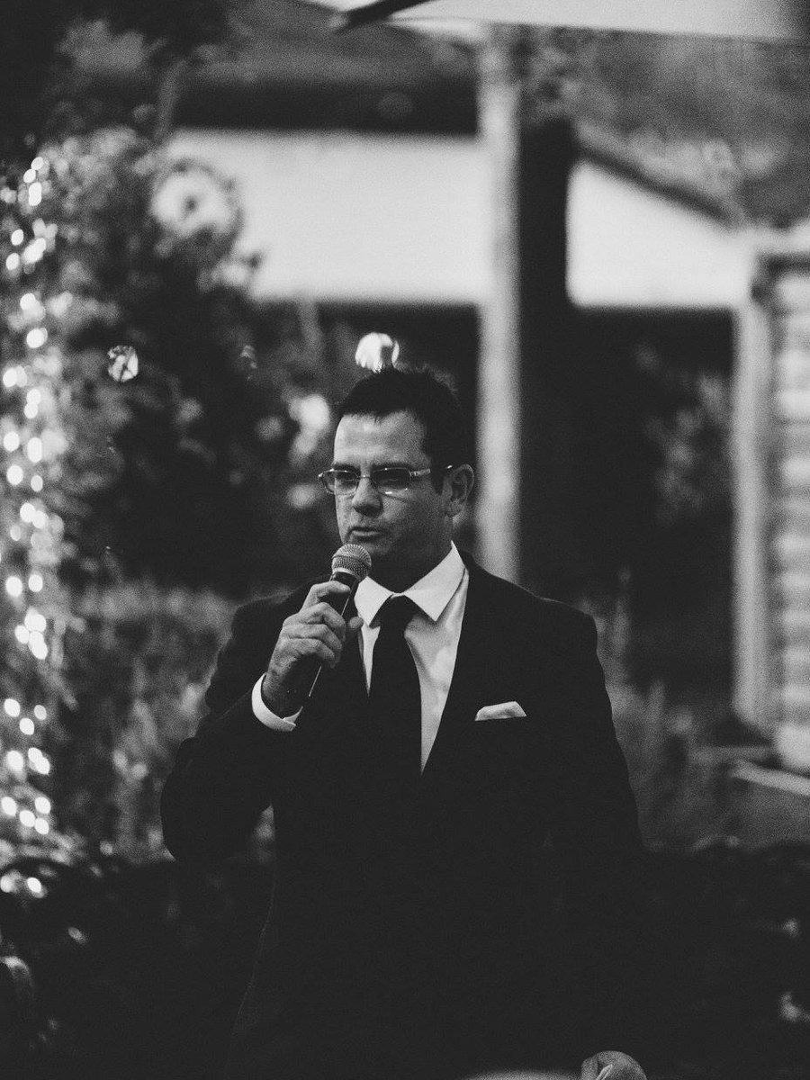 Shaun McEwan in black tie, speaking into a microphone