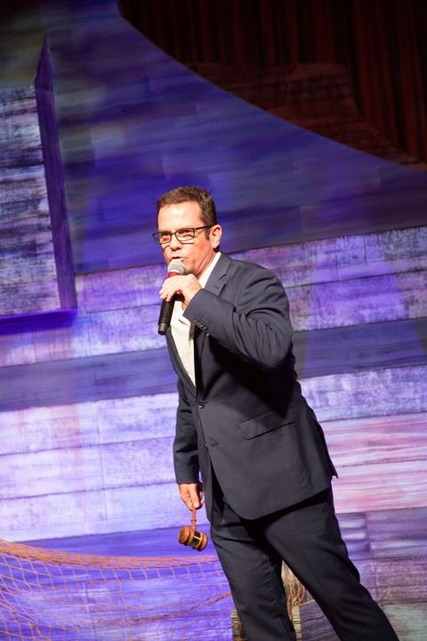 Auctioneer Shaun McEwan with gavel in hand on stage